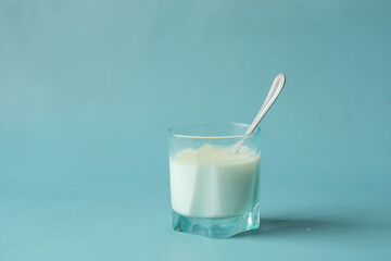  glass of milk and spoon on blue background 