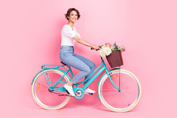 Full length photo of charming pretty lady wear white crop top riding bike smiling isolated pink...