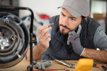 technician seeking help on the phone while repairing device