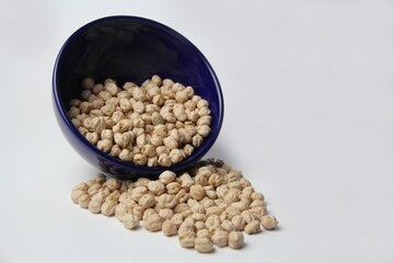 Chickpeas (Cicer arietinum) in a blue crockery bowl isolated on a white background. It is also known by the names: Gravanço, Herbanzo, Chicken Pea or Bengal Pea or Duck Grain.