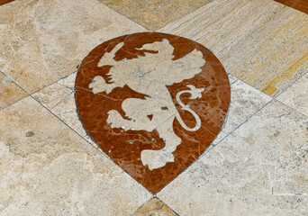 Detail of an old marble floor with the coat of arms of Grosseto, a griffin holding a sword, Tuscany, Italy