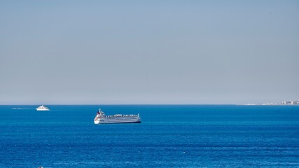 Transport ship and large luxury yacht sailing through the sea on a sunny day, off the coast of Malaga