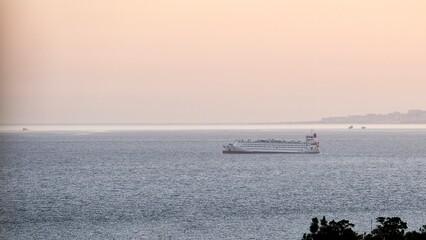 Transport boat sailing through the sea during sunset, off the coast of Malaga moving away from the city