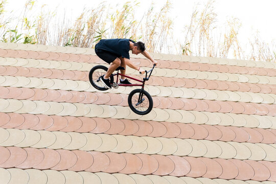 Young male riding BMX bike down slope