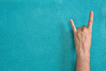 man hand rock and roll horns gesture on turquoise background