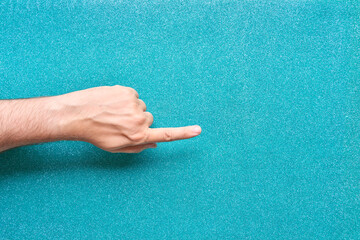 man hand pointing finger on glitter turquoise background coming out from the side