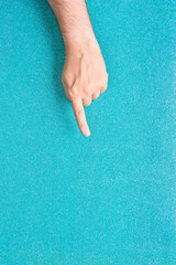 man hand pointing finger on glitter turquoise background coming out from below