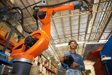 factory worker or engineer operating remote switch controller to control robot machine in the factory
