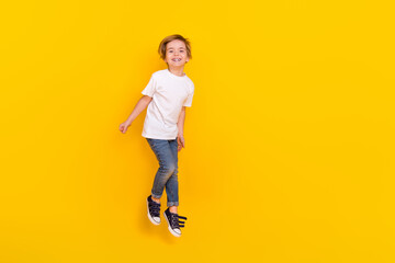 Fototapeta na wymiar Full length body size view of handsome cheerful funny pre-teen boy jumping having fun isolated over bright yellow color background