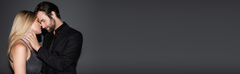 Side view of man in jacket touching stylish girlfriend on grey background, banner.