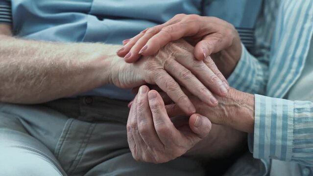 Senior couple, Taking care of the disabled partner. Concept about third age and real love and care. Close up on hands holding together.