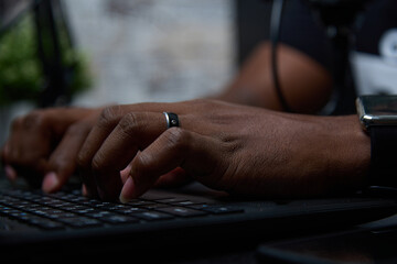 Close-up of the hands of a popular African-American blogger typing on a black keyboard. Black radio...