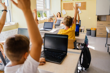 Active children pupils primary school raising hands during Informatics class. Internet technology....