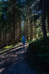 wandernde Frau im dunklen Tannenwald bei Sonntag-Stein im Grosswalsertal. Morgenstimmung im Wald....