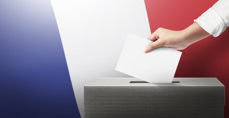 Close-up hand holding ballot paper into the voting box an France flag background. Freedom democracy concept. Freedom vote concept.