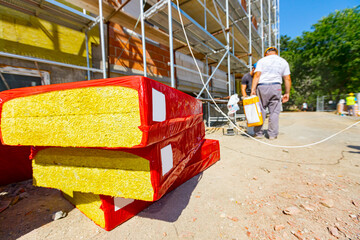 Stack of thermal insulation material is wrapped with cellophane foil. Unfinished edifice with...