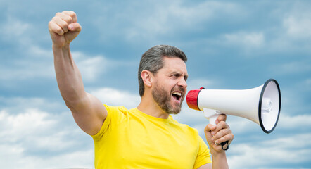 man in yellow shirt scream in megaphone on sky background