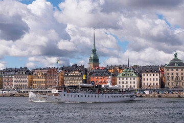 Fototapeta premium Old commuting steamboat in the bay Saltsjön leaving for the archipelago passing the old town Gamla Stan a sunny autumn day in Stockholm