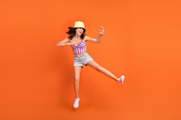 Fototapeta na wymiar Full length photo of sexy strong woman dressed violet bra jumping up practicing karate isolated orange color background