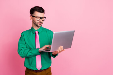 Photo of serious confident guy wear green shirt spectacles typing modern device empty space isolated pink color background