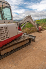Mini excavator in the process of repairing a street in a rural area