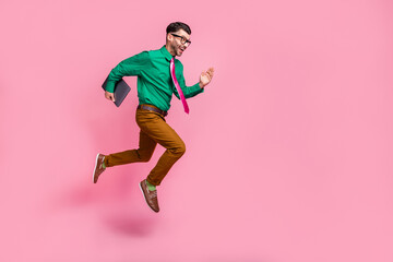 Plakat Full length photo of funky excited guy wear green shirt spectacles holding gadget jumping running empty space isolated pink color background