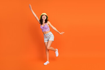 Fototapeta na wymiar Full length photo of excited dreamy woman dressed violet bra rising arm dancing empty space isolated orange color background