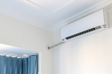 Air conditioner (ac) on white wall, turned on, cooling down interior during rising temperatures and...