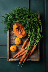 Fresh organic pumpkin and carrots with green leaves on wooden background. Vegetables. Healthy food