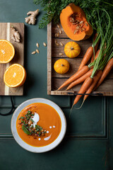 Vegetarian autumn pumpkin and carrot soup with cream, spicy chickpeas and radish micro greens. Comfort food, fall and winter healthy slow food