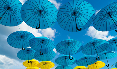 Blue and yellow umbrellas hanging bottom-up abstract sky background