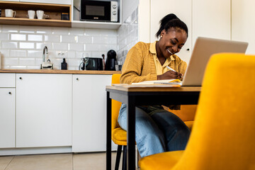 Young African American female student learning at home in living room.