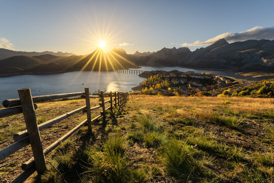 Picturesque landscape of town at riverside in mountainous valley at sunset