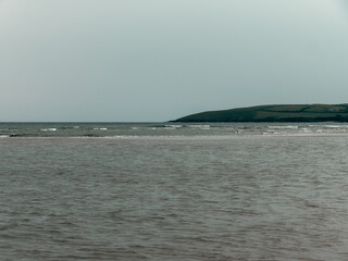 Cold sea on a cloudy day. A hill on the seashore. Seascape. Ocean waves
