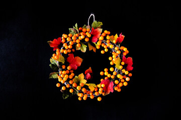 華やかな秋のオレンジ色の葉や実のリース（黒色の背景）