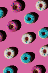 Trendy sunlight seamless pattern made of three colorful doughnut toys with sharp shadow on bright pink background. Minimal food summer concept with copy space..