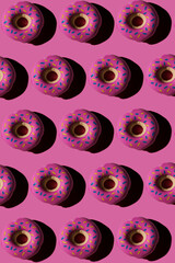 Trendy sunlight seamless pattern made of three colorful doughnut toys with sharp shadow on bright pink background. Minimal food summer concept with copy space..