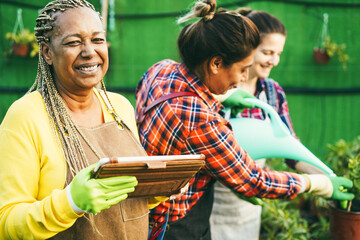 Multiracial women working inside greenhouse garden - Nursery and spring concept