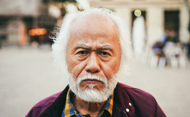Asian senior man looking at camera outdoor - Focus on face