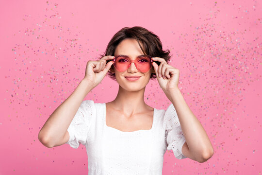 Photo of adorable pretty lady wear white blouse arms heart glasses flying confetti isolated pink color background