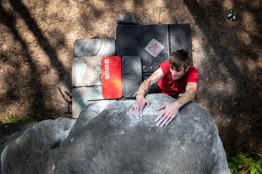 Athletic young man is jumping for top hold in famous and hard dyno boulder problem called "Cannon ball - 7b". Fontainbleau, France, Europe.