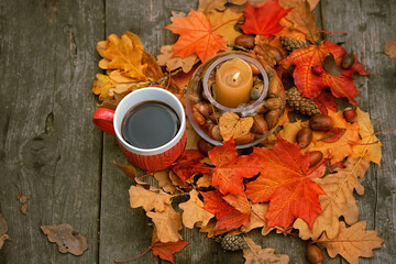 tea cup, candle lantern, autumnal leaves, acorns and cones on wooden table. Autumn background. fall...