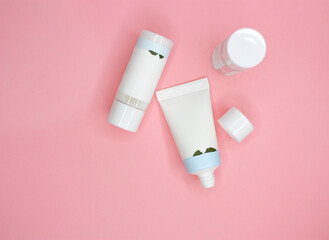 Flat lay with blank cosmetic products lotion, cleanser, tonic, essence, cream on pink background. Top view. Hygiene bottles. Dermatology, cosmetology. Beauty concept mock up. Selective focus.