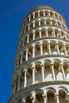 Pisa, Toscana , Italia 08-28-2022.  A picturesque portrait shot of the famous Pisa Leaning Tower on a beautiful day at dusk with a blue sky, and the sun shines on the white marbled campanile.