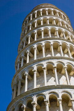 Pisa, Toscana , Italia 08-28-2022.  A picturesque portrait shot of the famous Pisa Leaning Tower on a beautiful day at dusk with a blue sky, and the sun shines on the white marbled campanile.
