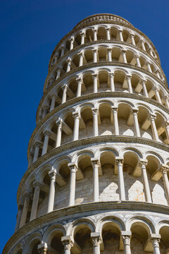 Pisa, Toscana , Italia 08-28-2022.  A picturesque portrait shot of the famous Pisa Leaning Tower on a beautiful day at dusk with a blue sky, and the sun shines on the white marbled campanile.