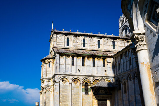 Pisa, Toscana , Italia 08-28-2022.  A picturesque portrait shot of the famous Pisa Leaning Tower on a beautiful day at dusk with a blue sky, and the sun shines on the white marbled campanile.