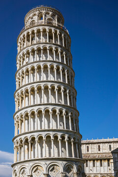 Pisa, Toscana , Italia 08-28-2022.  A picturesque portrait shot of the famous Pisa Leaning Tower on a beautiful day at dusk with a blue sky, and the sun shines on the white marbled campanile.