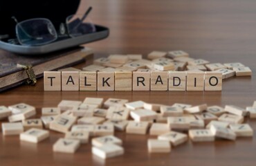 talk radio word or concept represented by wooden letter tiles on a wooden table with glasses and a book