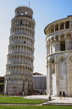 Pisa, Toscana , Italia 08-28-2022.  A picturesque portrait shot of the famous Pisa Leaning Tower on a beautiful day at dusk with a blue sky, and the sun shines on the white marbled campanile.